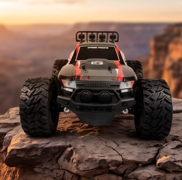 Yile Storm RC Truck - Canyon Overlook Red and grey Yile Storm RC truck parked on a rock ledge above a canyon at sunset